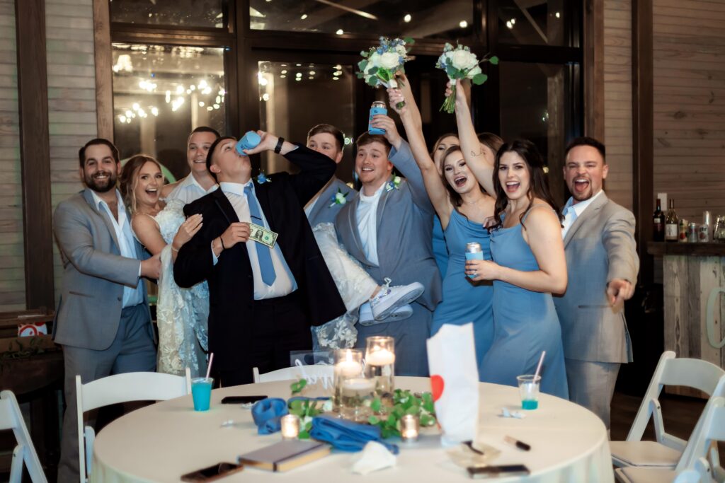 photo of wedding party celebrating at reception with bride and groom
