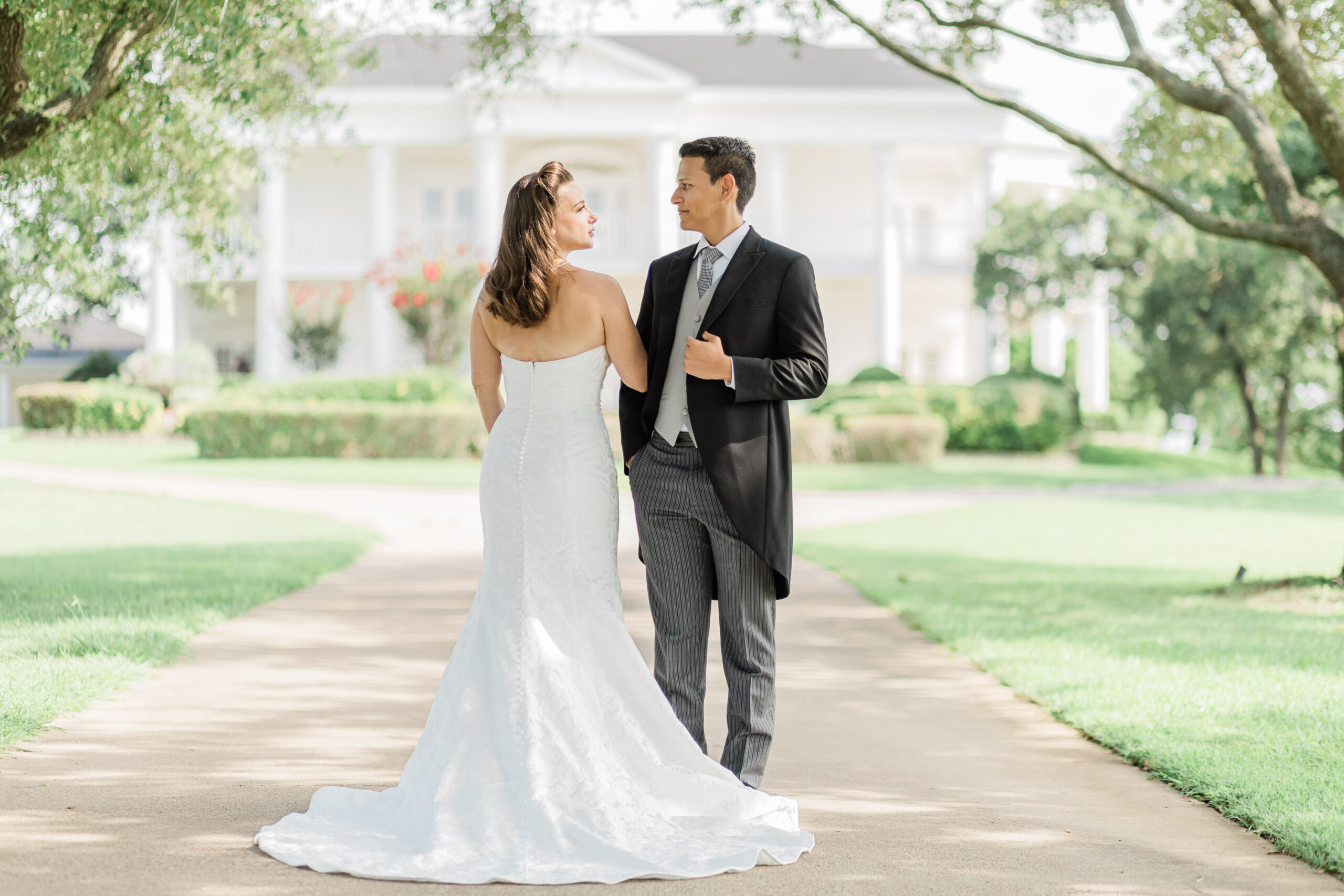 Bride and groom portrait on driveway outside a colonial mansion.